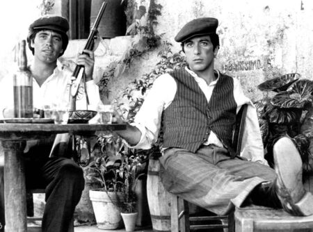 Portrait sombre et intense d'Al Pacino dans le rôle de Michael Corleone dans le film Le Parrain, portant un costume cravate, regardant hors champ.