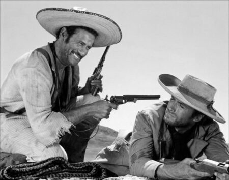 Photographie noir et blanc de Eli Wallach pointant un revolver vers Clint Eastwood qui est allongé au sol, scène culte du film Le Bon, la Brute et le Truand.