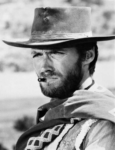 Affiche Eastwood Regard Acier : Gros plan en noir et blanc du visage de Clint Eastwood portant un chapeau de cowboy et un cigare aux lèvres, expression intense.