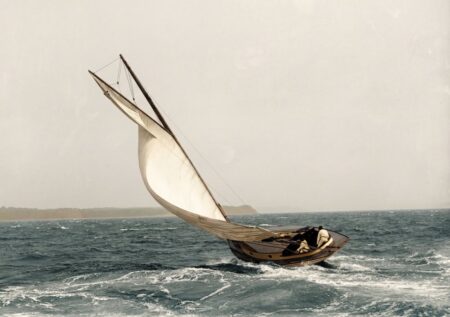 Affiche d'une photo historique colorisée de Fuzars montrant un voilier du début du 20ème siècle naviguant sur une mer agitée avec un équipage réduit.