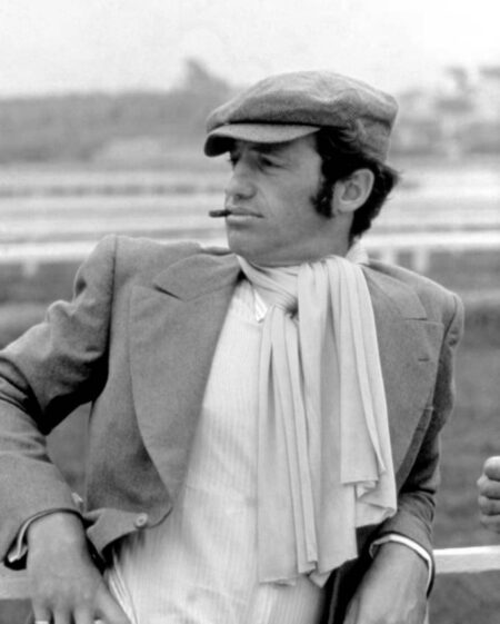 Affiche Belmondo Le Magnifique : Portrait noir et blanc de Jean-Paul Belmondo accoudé à une barrière, portant une casquette, une écharpe blanche et fumant un cigare
