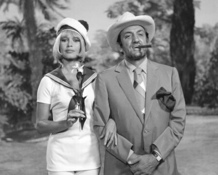 Photographie en noir et blanc du film Boulevard du Rhum montrant Lino Ventura avec un cigare à la bouche et brigitte bardot en marin qui le tient par le bras