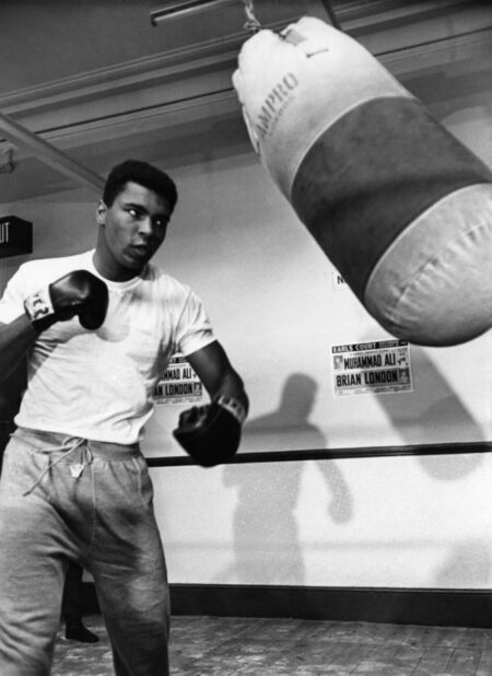 Affiche Mohamed Ali : photographie vintage en noir et blanc de Mohamed Ali s'entraînant avec un sac de frappe en 1966 à Londres.