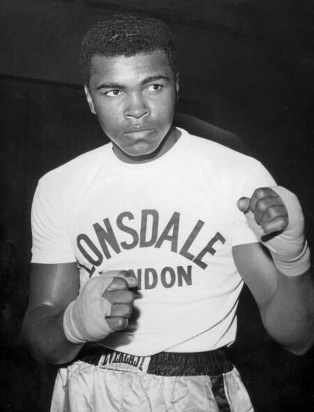 Affiche Mohamed Ali : photographie vintage en noir et blanc de 1963 montrant Cassius Clay (Mohamed Ali) portant des gants de boxe, s'appuyant sur les cordes d'un ring dans une pose pensive.