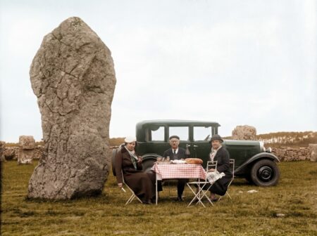 Photo colorisée des alignements de menhirs de Carnac en Bretagne vers 1930. Un groupe de personnes pose près des mégalithes et d'un panneau "PROPRIÉTÉ DE L'ÉTAT".