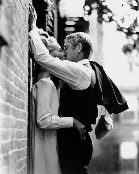 Photographie noir et blanc de Steve McQueen et Faye Dunaway s'embrassant passionnément contre un mur de briques, scène du film L'Affaire Thomas Crown.