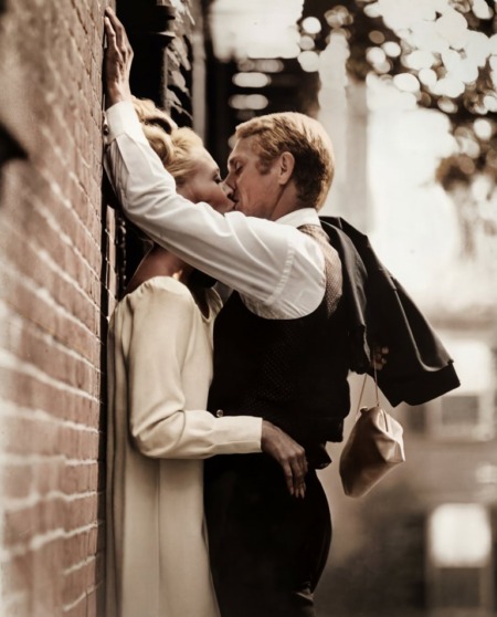 Photographie noir et blanc de Steve McQueen et Faye Dunaway s'embrassant passionnément contre un mur de briques, scène du film L'Affaire Thomas Crown.