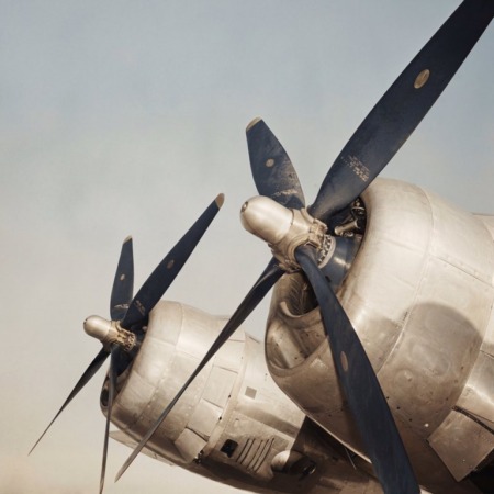 Affiche Moteurs Avion Vintage : photographie d’art colorisée en gros plan montrant les deux moteurs à hélices bleues d'un avion de ligne légendaire des années 1940, type Douglas DC-3, sur un ciel clair.