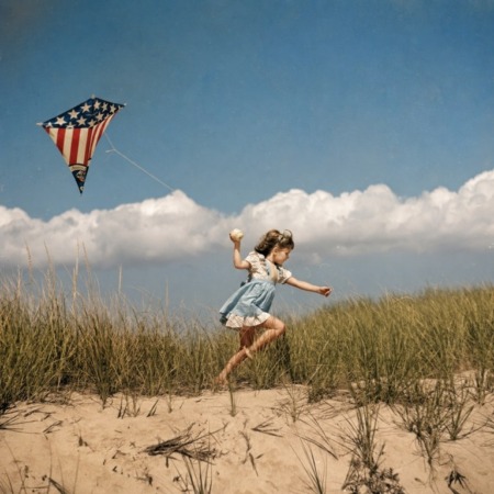 Affiche Cerf-Volant Vintage Plage : photographie d'art colorisée des années 50 montrant une petite fille courant dans les dunes avec un cerf-volant aux couleurs du drapeau américain sous un ciel d'été parsemé de nuages.