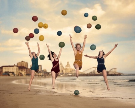 Affiche Plage Vintage Joie : photographie d'art des années 30 montrant quatre femmes en maillot de bain sautant de joie sur une plage avec des ballons.
