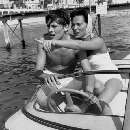 Affiche Alain Delon Cannes : photographie d'art en noir et blanc de 1958 montrant un jeune Alain Delon torse nu au volant d'un hors-bord avec l'actrice Bella Darvi sur la mer à Cannes.