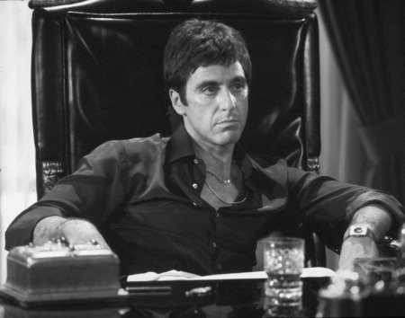 Affiche Scarface Al Pacino : photographie d'art en noir et blanc de 1983 montrant Al Pacino dans le rôle de Tony Montana assis dans un grand fauteuil en cuir noir derrière son bureau, regard intense.