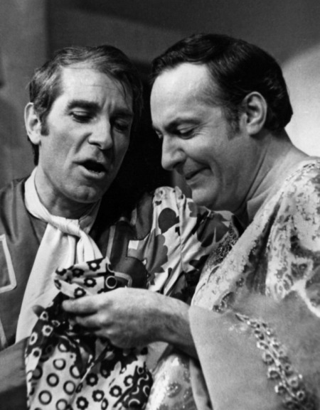 Affiche Poiret Serrault La Cage aux Folles : photographie d'art en noir et blanc montrant Jean Poiret et Michel Serrault en costumes de scène extravagants, complicité en coulisses pour la pièce de théâtre culte.