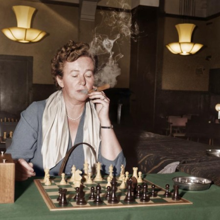 Affiche Ingrid Larsen Échecs : photographie d’art colorisée de 1954 montrant la championne danoise Ingrid Larsen en pleine concentration lors d'un tournoi à Amsterdam, un cigare à la main avec d'épaisses volutes de fumée s'élevant au-dessus de l'échiquier.